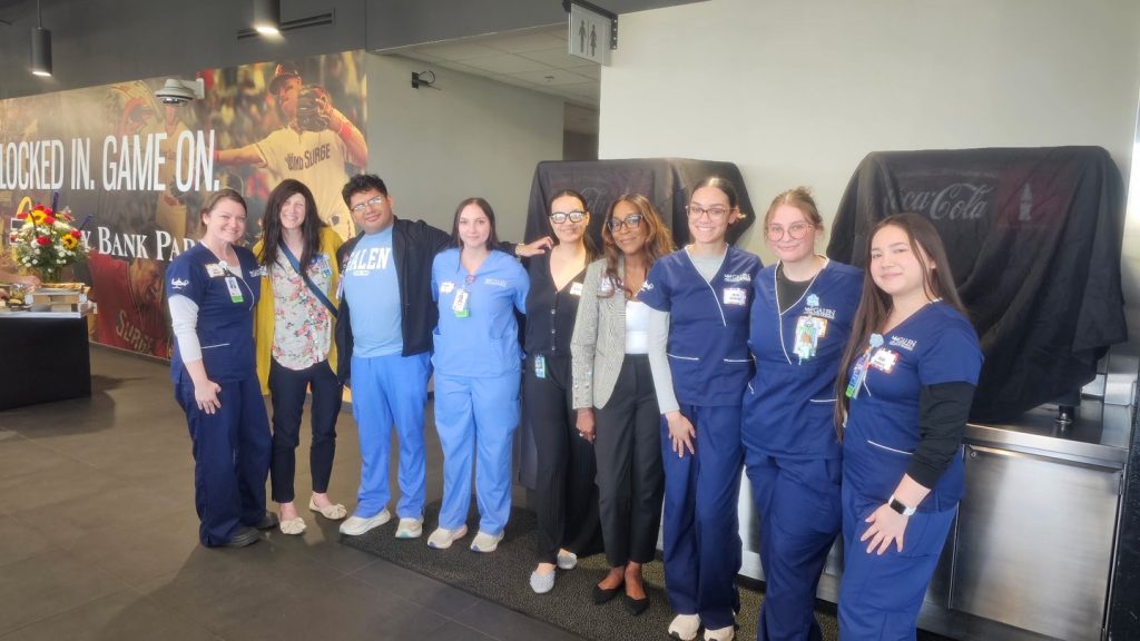 Group of nursing students and staff posing together at an indoor venue, with event signage and food service setup visible in the background. Attendees included Keisha Brooks, Dean; Alexis Carter, CES; Tosha Williams; Lauren Myers; cousins Aliyah and Tyesa Chalmers.
