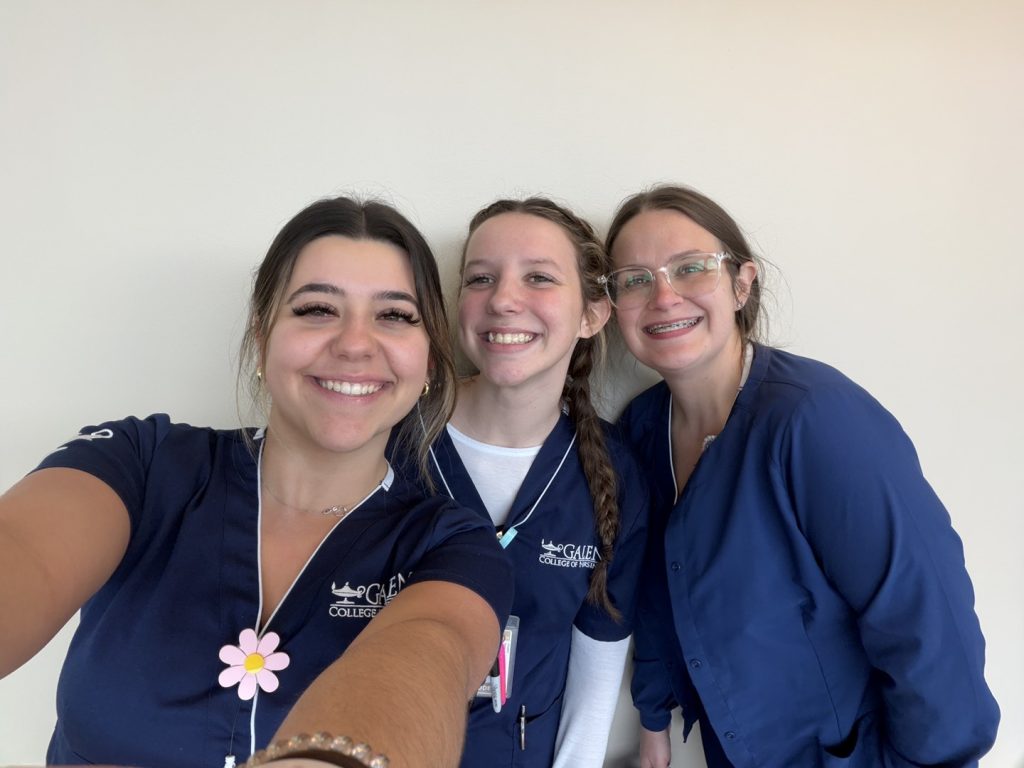Three students in Galen nursing scrubs smile for a close-up selfie.
