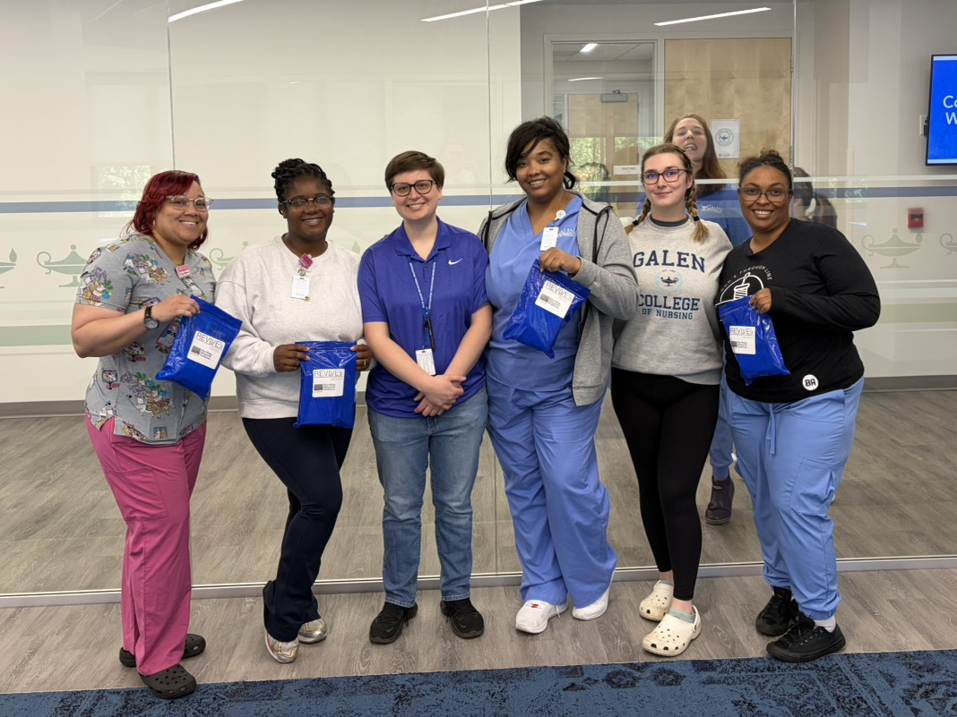 Group of Galen College of Nursing students and staff holding blue REVIVE overdose response training kits.
