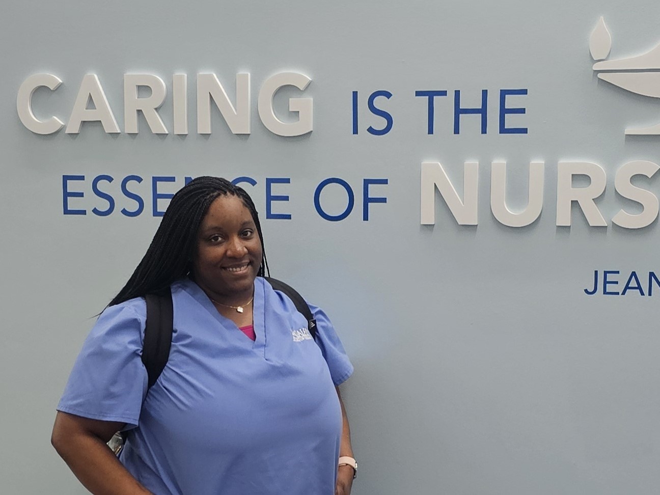 Leslie Frazier poses in front of the Caring wall at Gainesville's Galen campus.
