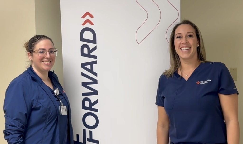 Melissa Alvarez and Nichole Urban wearing HCA Florida scrubs, standing in front of a wall with the word “Forward.”
