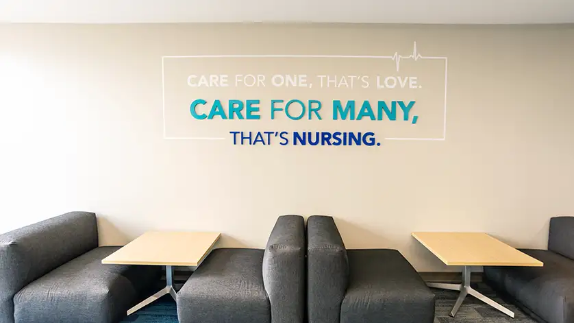 Booth seating in a commons area of Galen College in San Antonio, with a wall that reads Care for one, that's love. Care for many, that's nursing.