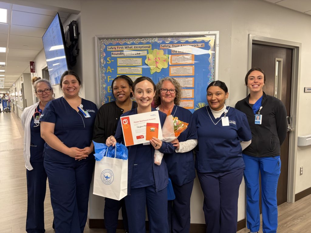 Healthcare team members stand together in a hallway celebrating a student holding a Flower Bud Award.