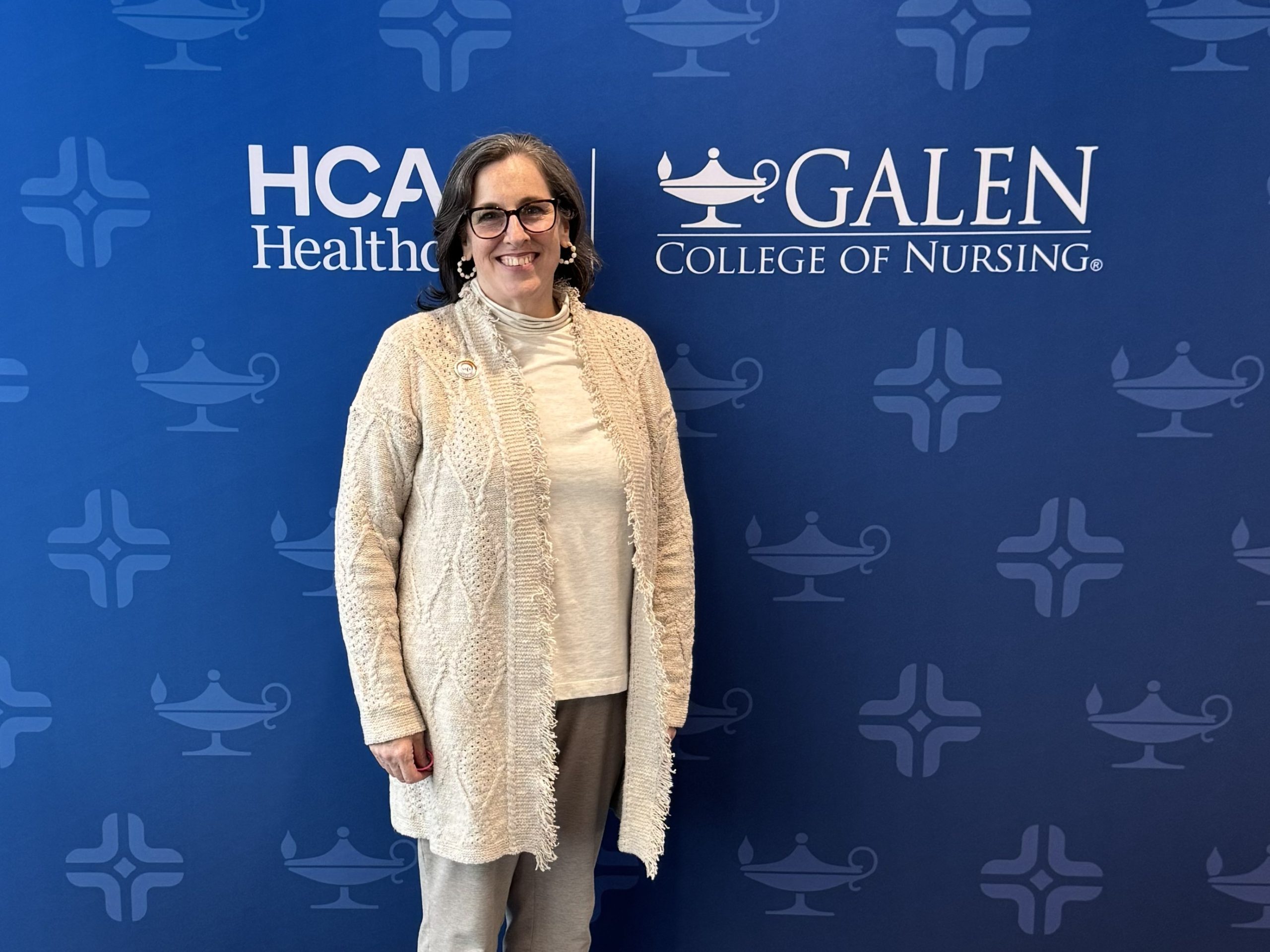 Individual stands in a conference-style space in front of a branded HCA Healthcare and Galen College of Nursing backdrop.