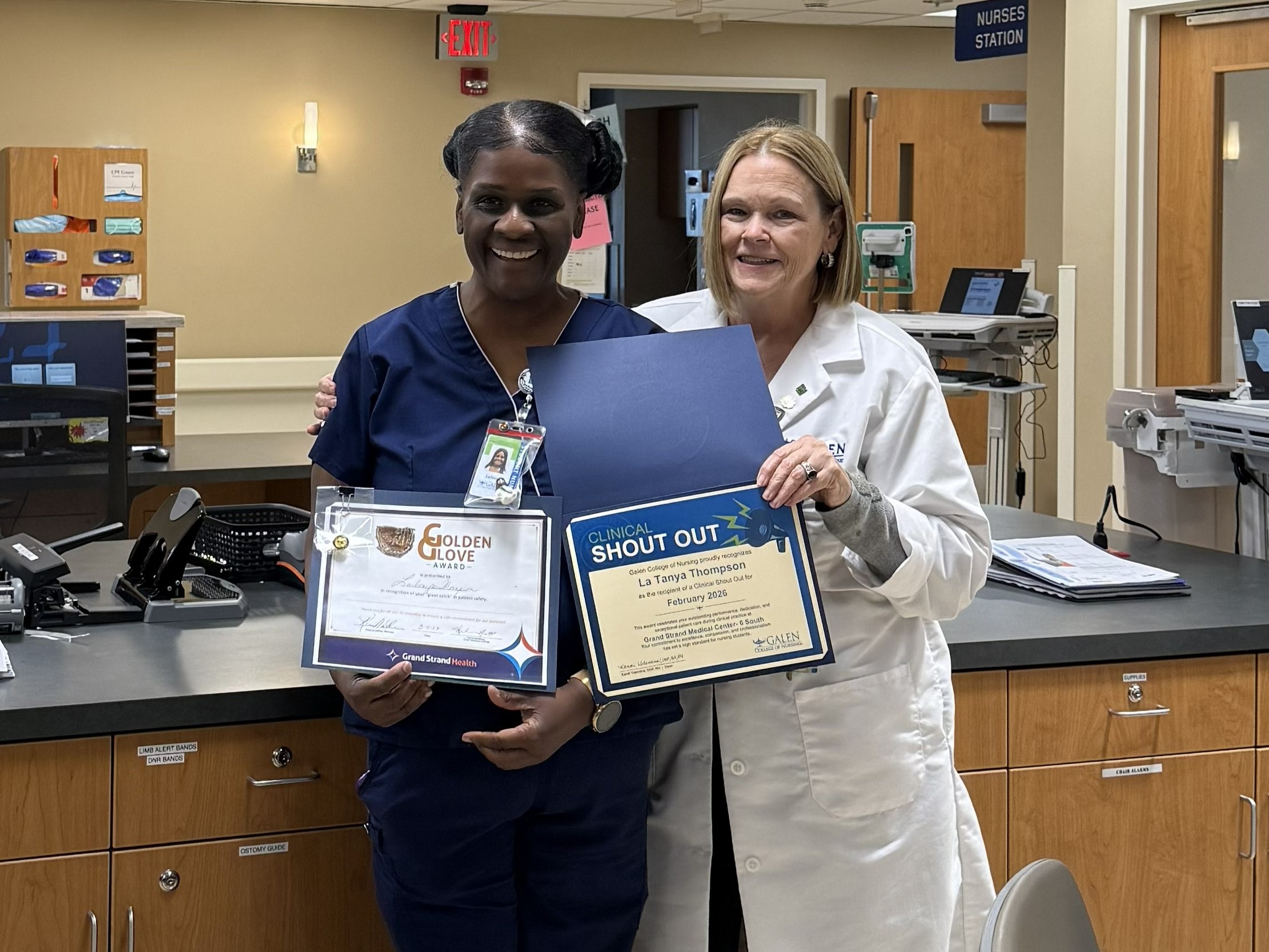 Healthcare staff member presents recognition certificates to a Galen College of Nursing student at a nurses station