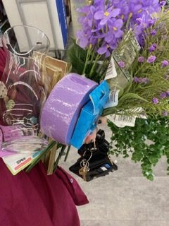 Close-up of wedding decorations on a hospital counter, including purple flowers, ribbon, vases, and various decorative supplies used to prepare a small ceremony.