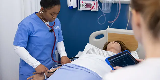 nursing student with stethoscope checking a patient in the simulation lab at Galen