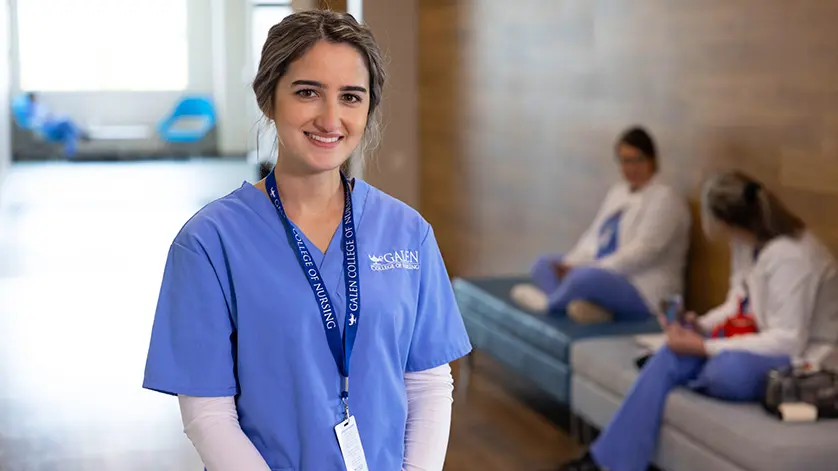 young woman nursing student in scrubs, smiling at the camera and standing in a corridor at a Galen campus